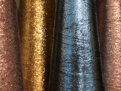 L'effet métallisé, brillant ou pailleté a toujours fasciné, associé symboliquement à la lumière, au soleil, à la sophistication. L'invention du Lurex remonte au XXe siècle, en 1946 plus précisément. Fil textile de polyester recouvert d'une couche de métal aux effets brillants ou scintillants, le Lurex est un fil léger et souple qui existe dans une vaste palette de coloris. 